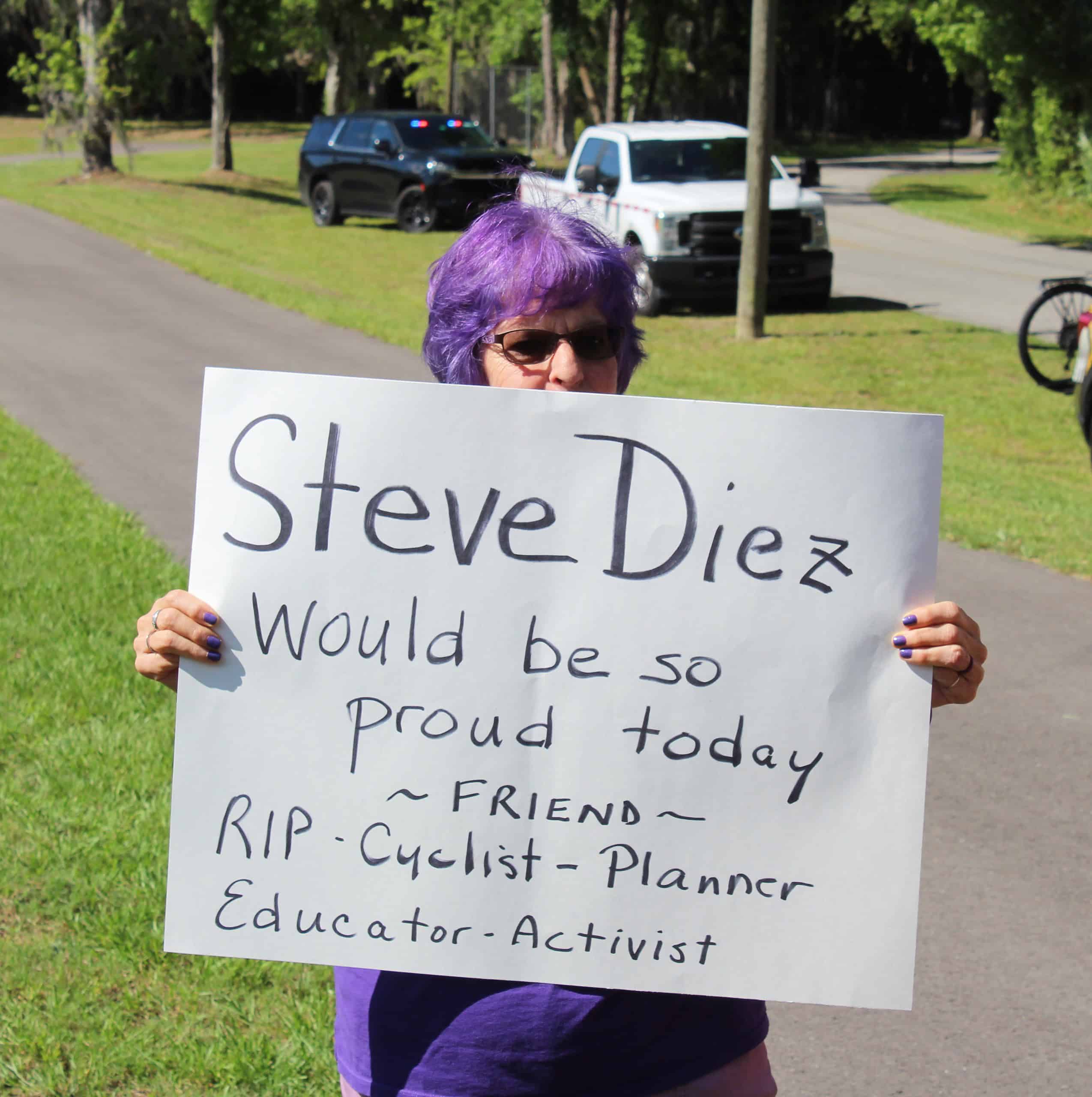 An attendee at Wednesday's grand opening holds a sign in the memory of Steve Diez, a transportation planner who was critical in the completion of the trail. [Photo by Austyn Szempruch]