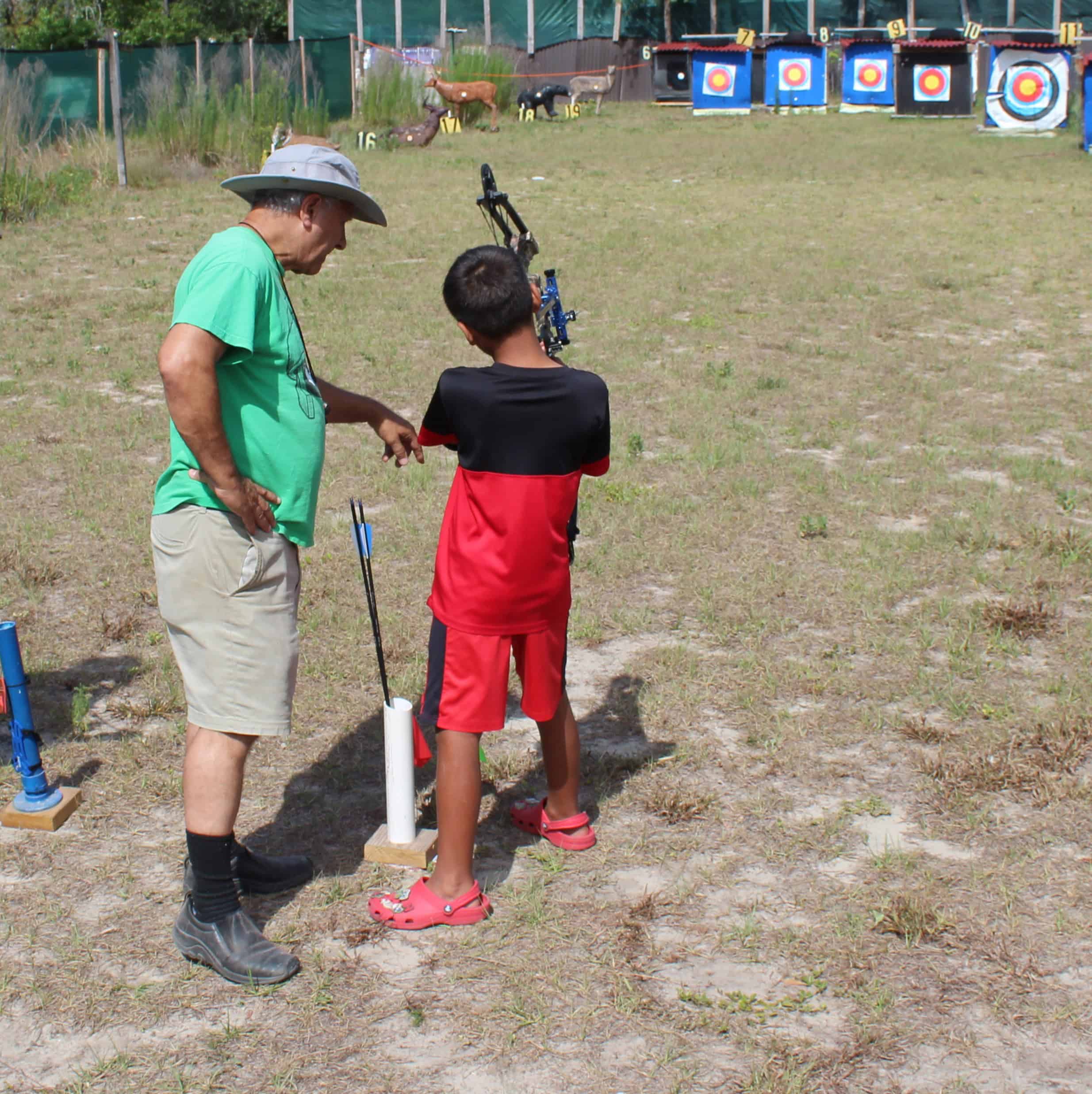 Citrus Archery Club President David Ireland helps a young archer with his bow on Saturday. [Photo by Austyn Szempruch]