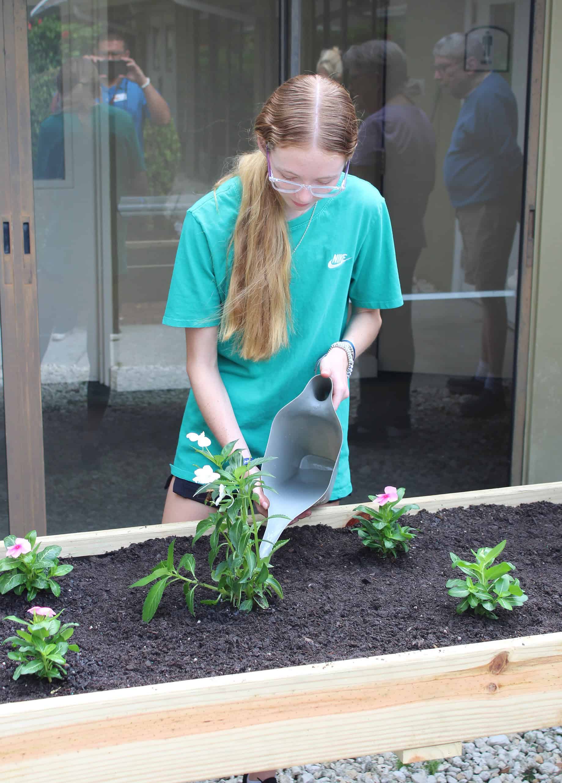 Girl Scout Kaitlyn Cox Waters Flowers at Vitality Living Spring Hill on Friday. [Photo by Austyn Szempruch]