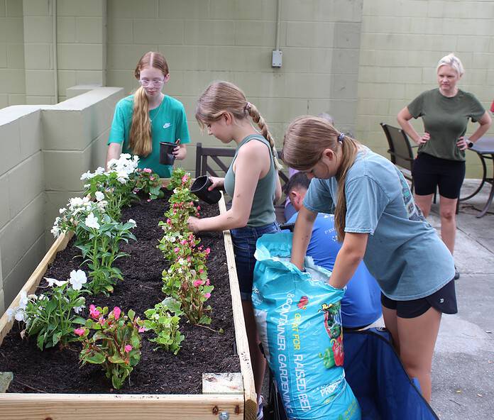 (Left to right) Girl Scouts Kaitlyn Cox, Sophia Mazza, and Allie Licht plant flowers for seniors at Vitality Living on Friday. [Photo by Austyn Szempruch]