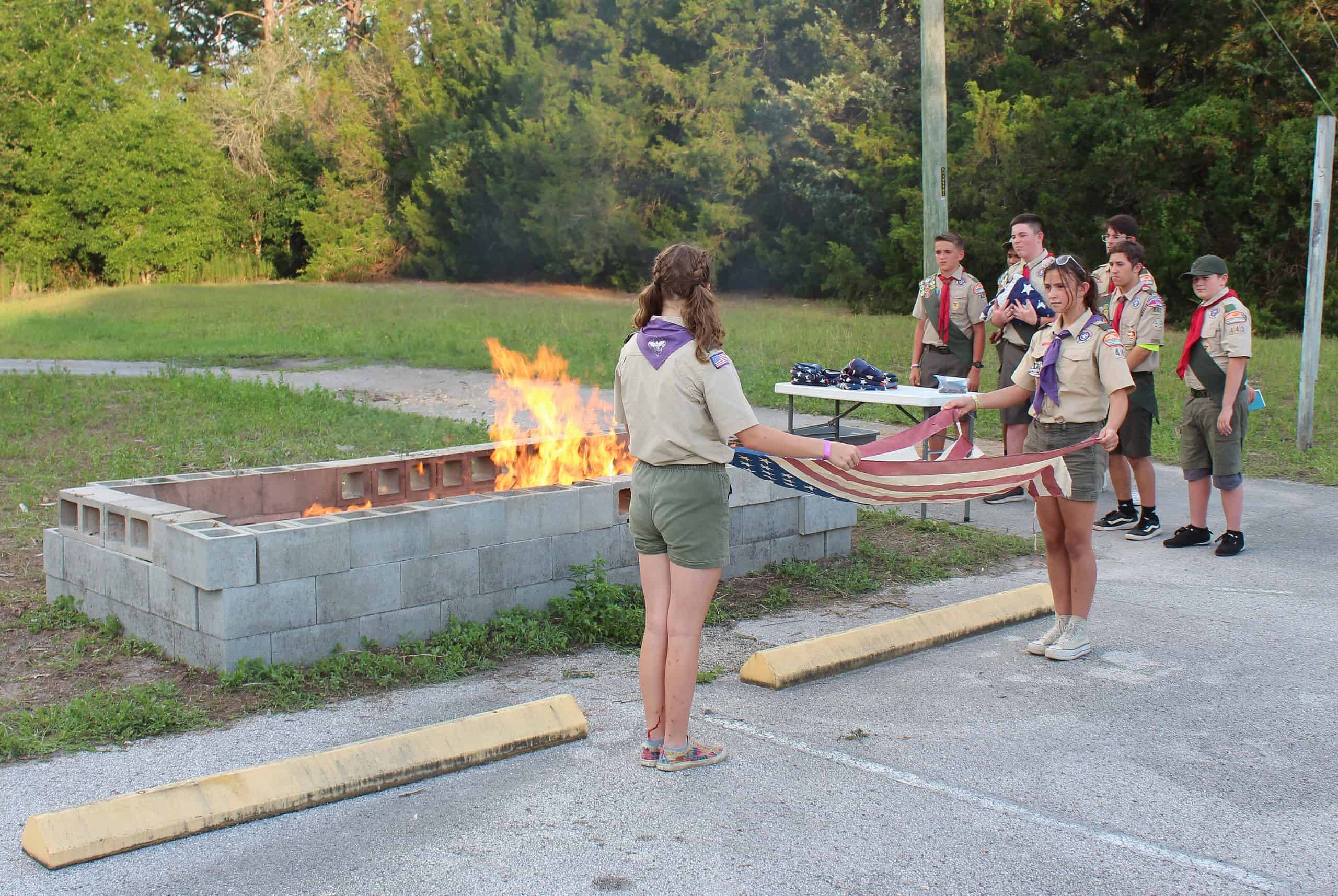 Members of the local girls' scout troop prepare to retire one of the 30 American flags on Friday [Photo by Austyn Szempruch]