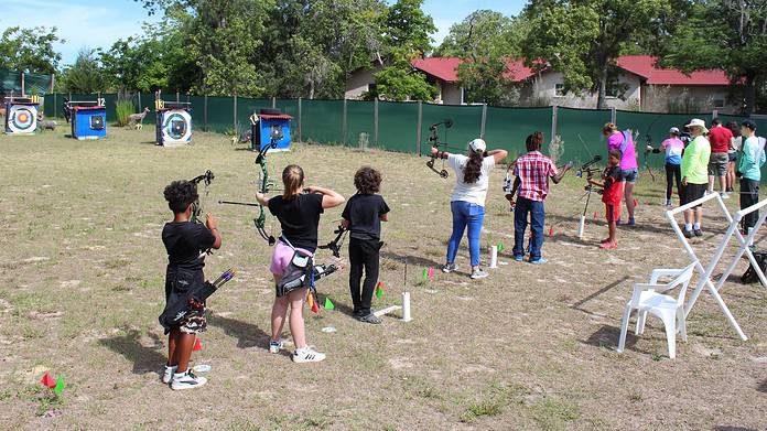Club member Patrick Herbert (bright green shirt) instructs archers during Citrus Archery's Summer Youth Days. [Photo by Austyn Szempruch]