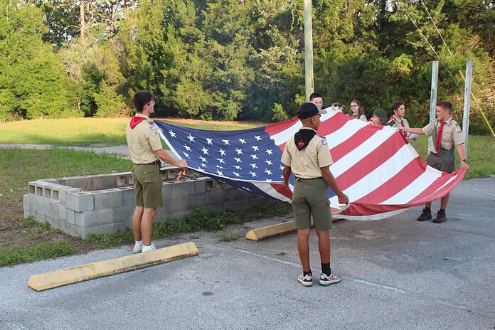 Members of the local boys' scout troop prepare to retire one of the 30 American flags on Friday [Photo by Austyn Szempruch]