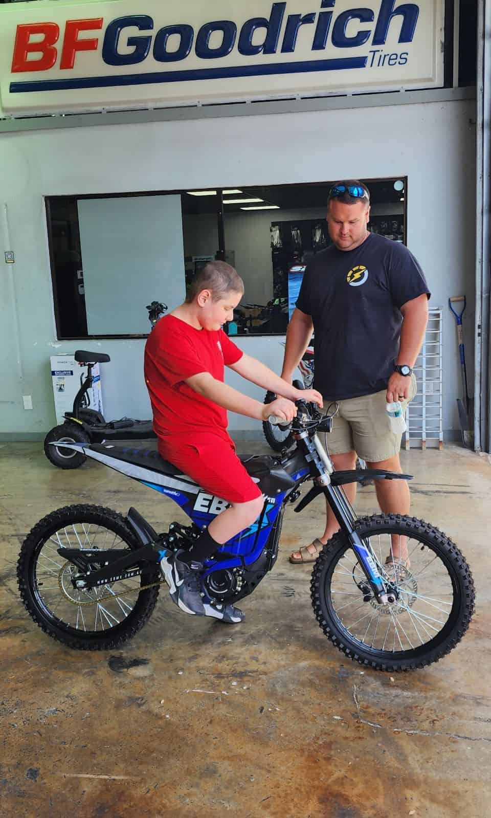 Aaron Nations (right) helps Deegan Giglio feel comfortable on his new electric motorbike. [Photo by Austyn Szempruch]