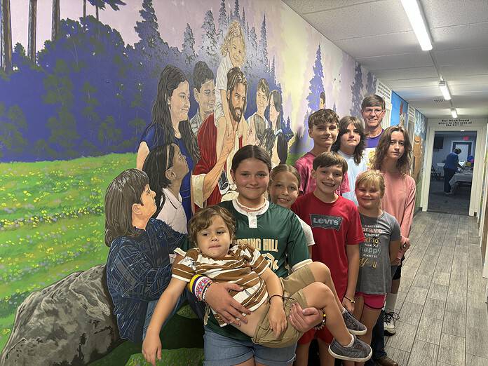 Youth members of Garden Grove Baptist Church pose in front of a newly finished mural at the church painted by Tom Ammons (back row), the children's deacon at Garden Grove. The mural is an interpretation of Jesus and The Children and the children are in the likeness of actual church members. [Courtesy photo]