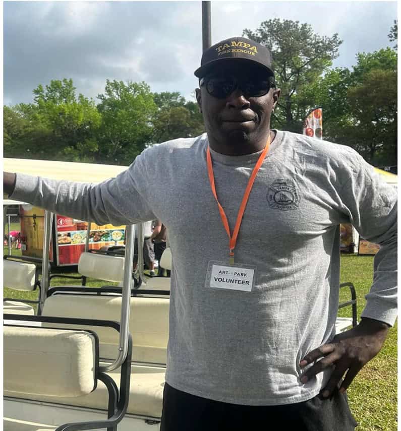 This photo of Marvin Baynham volunteering at Art in the Park was altered by dark money group Voters Response using AI to replace his fire department logos on his shirt and hat with Biden Harris logos.