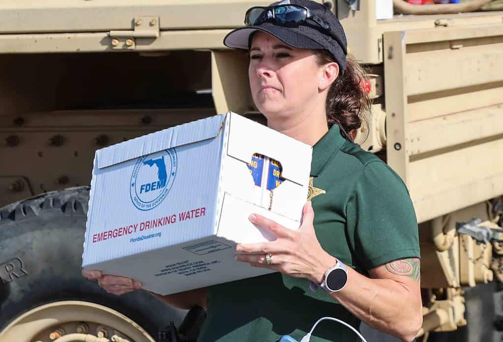 A deputy carries a case of water to a resident. [Credit: Mark Stone]