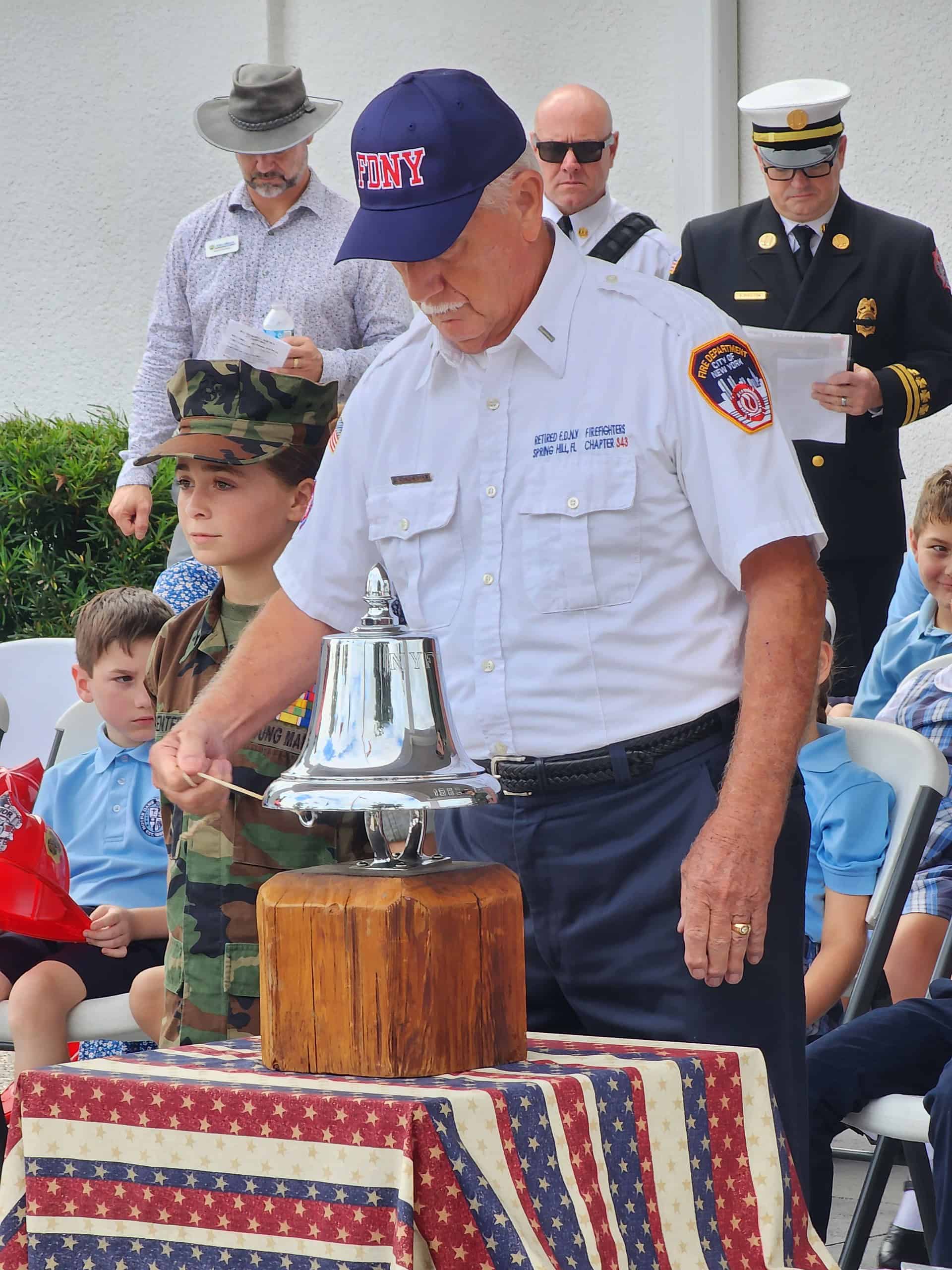 Firefighter Dan Chichester performs the ringing of the bell ceremony at Wednesday's 9/11 remembrance. [Photo by Austyn Szempruch]