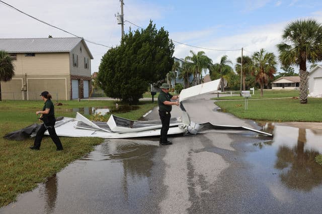 Deputies work to clear roofing from a roadway in Hernando Beach. [Credit: Mark Stone]