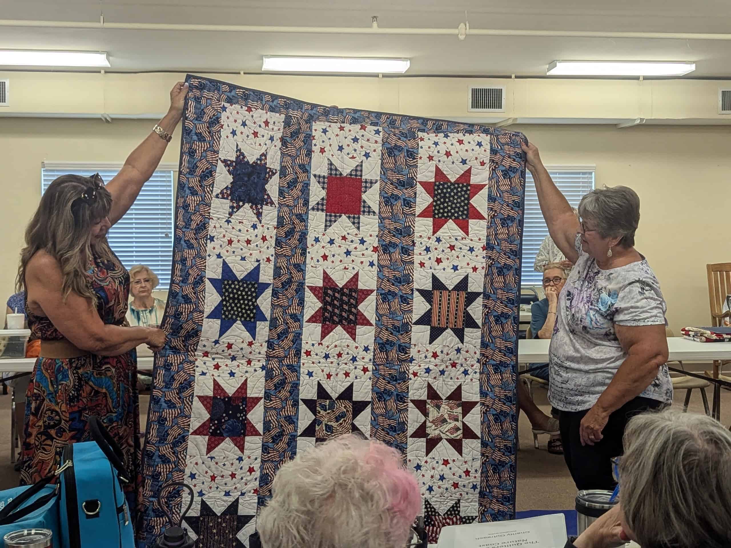 Mary Ann Delvalle holds up her Quilt of Valor with program coordinator Dale Wenner. [Credit: Julie Maglio]