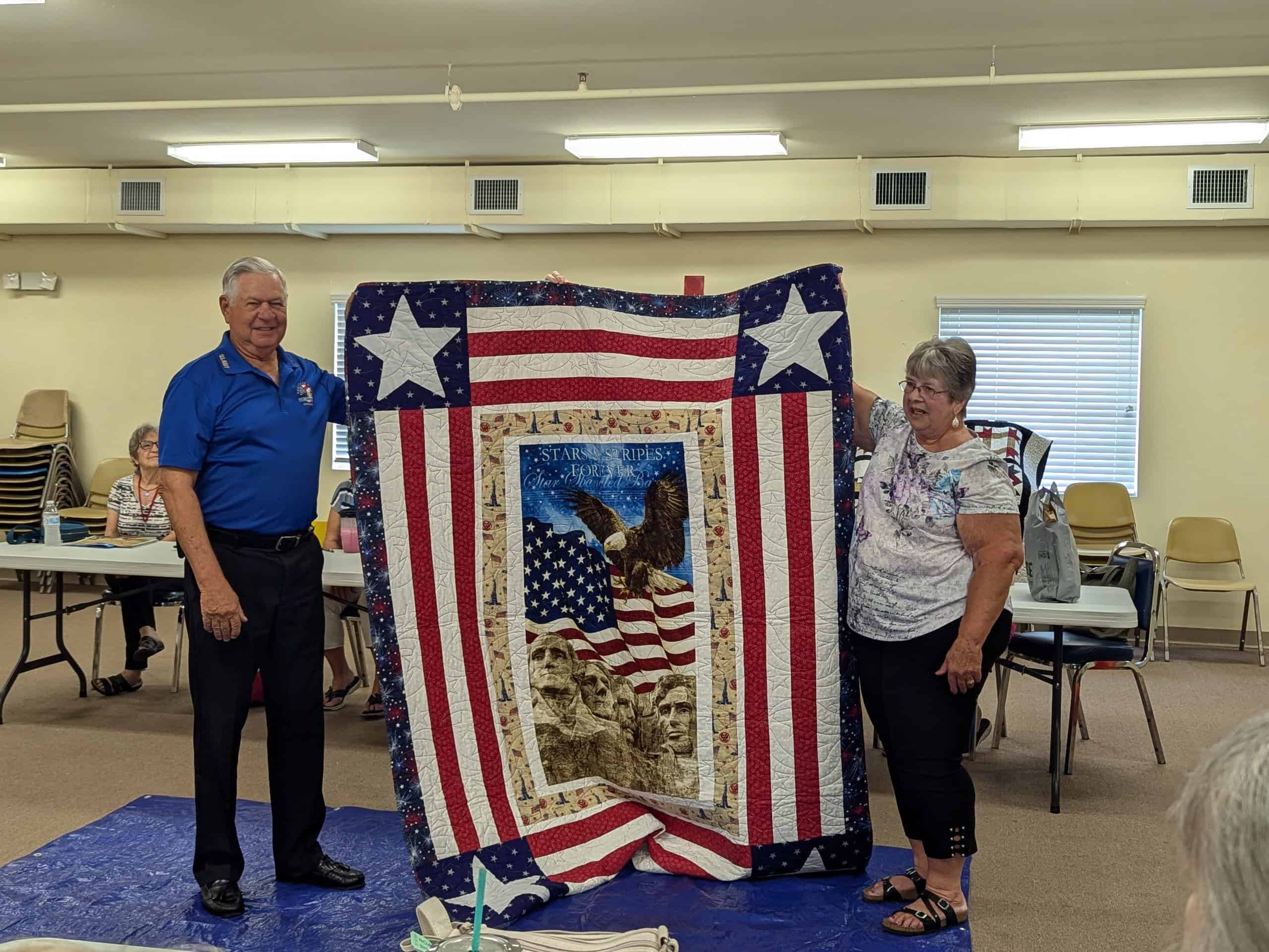 William Stoehs holds up his Quilt of Valor with program coordinator Dale Wenner. [Credit: Julie Maglio]