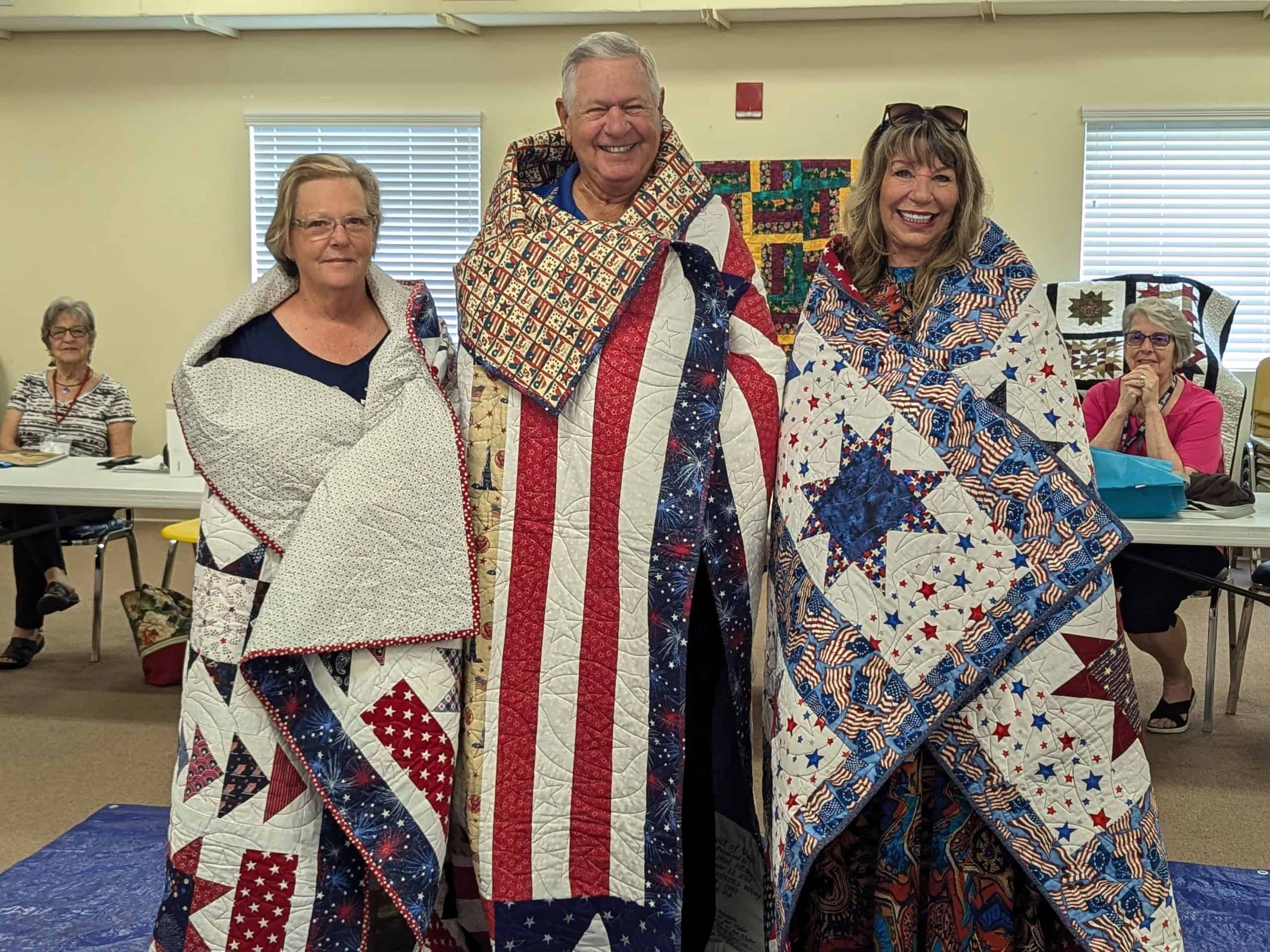 All wrapped up Quilts of Valor from left to right: Alice Reid, William Stoehs and Mary Ann Delvalle. [Credit: Julie Maglio]