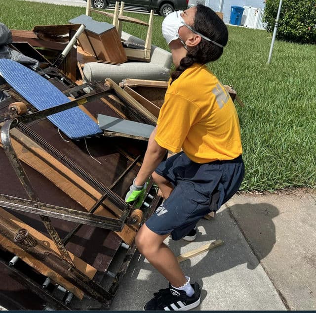 Cadet Violet Fratichelli works to move water-soaked furniture from a Hernando Beach residence. [Photo: CHSNJROTC / Facebook]