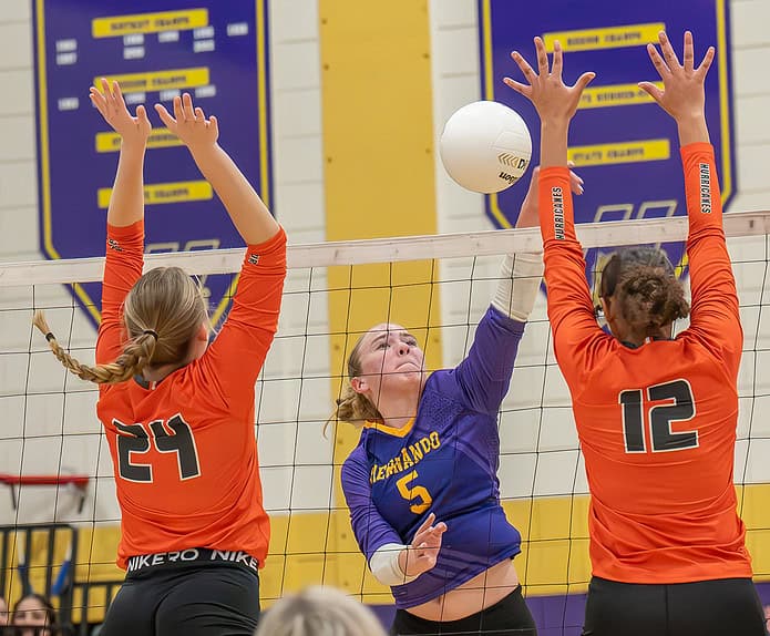 Hernando High ,5, Katie Charlow sends a kill shot between Mt Dora High School defenders Wednesday during the 4A region quarterfinal match in Brooksville. [Photo by Joe DiCristofalo]