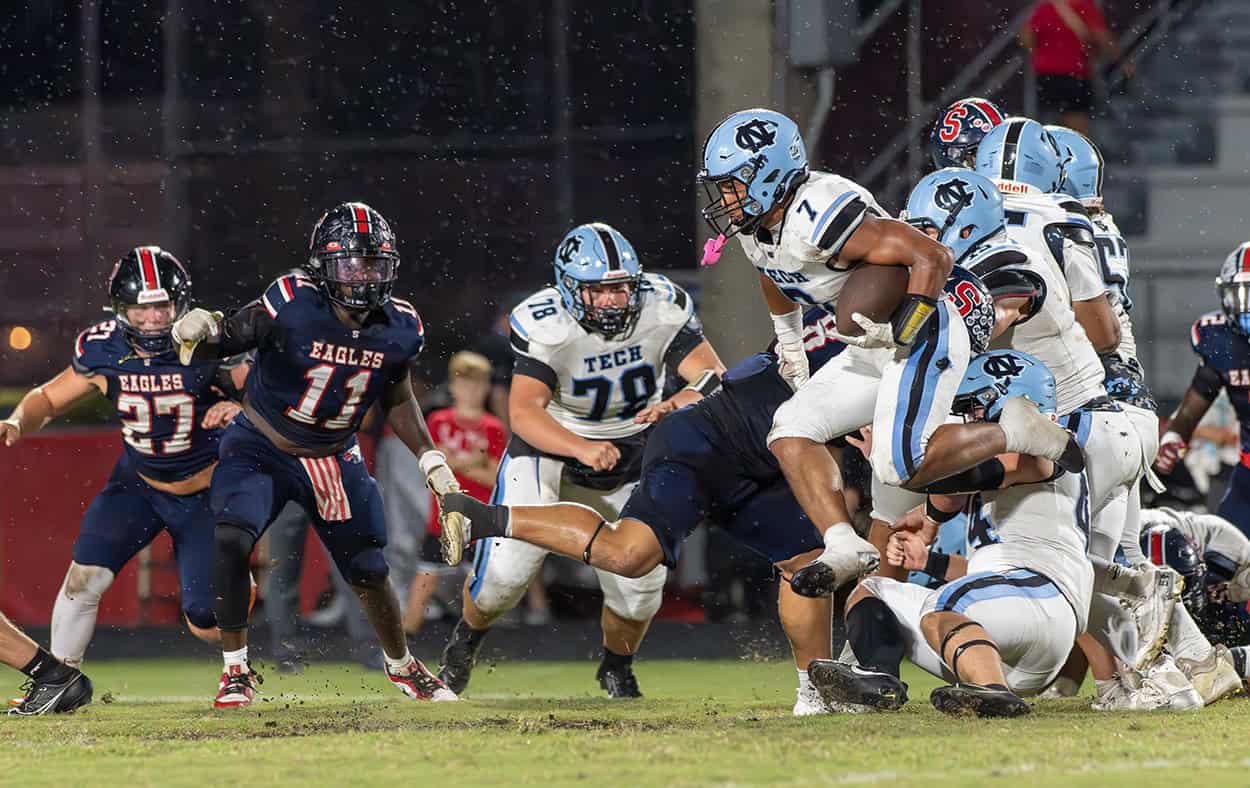 Nature Coast Tech, 7, LJ Elwin hurdles a teammate before taking on Springstead defenders, 11, James Hicks and 27, Dalton Williams Friday at Booster Stadium. [Photo by Joseph DiCristofalo]