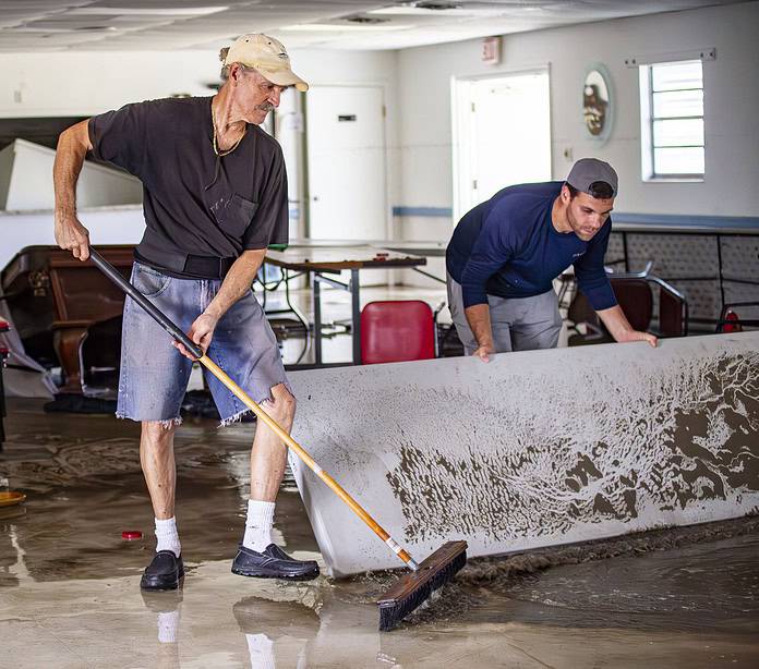 John Paul Reeve, president of the Marine Safety Group, sweeps water out of the Coast Guard Auxiliary Building. [Credit: Hanna Maglio]