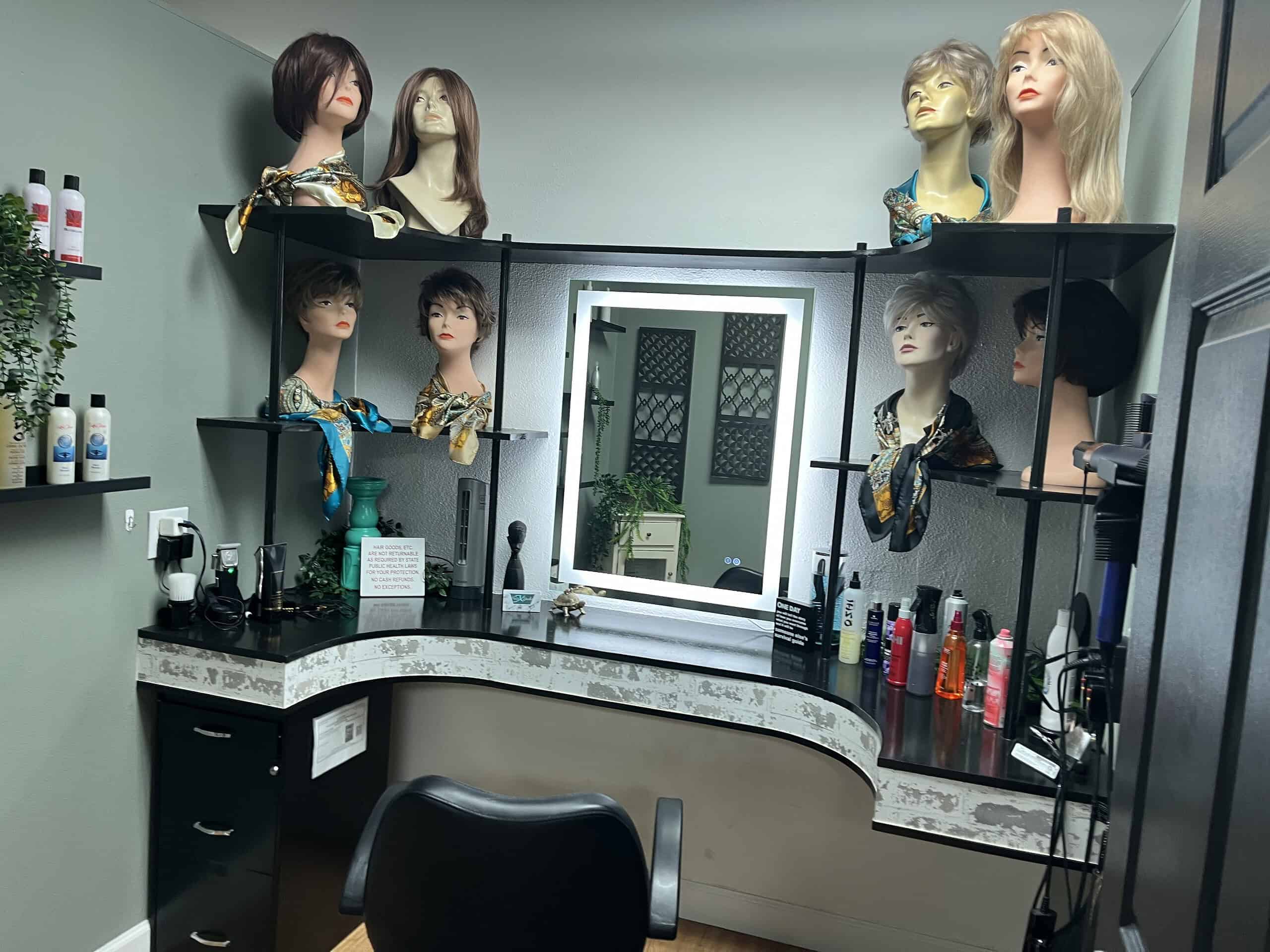 Wigs displayed in one of the private consultation rooms at Hair Studio 10. Red, blond, black and brown, wavy and straight, short or long, clipped bobs and dramatic falls. The salon has so many varieties. Most of the salon’s clients have lost their hair for medical reasons. [Photo credit: Sue Quigley]