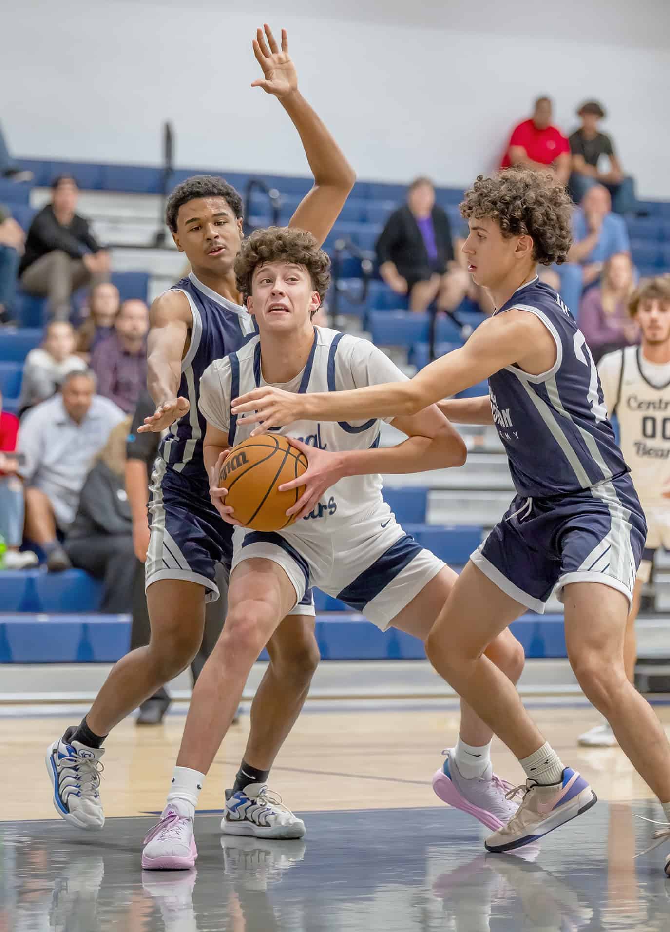 Central High, 35, Alejandro Canales is swarmed under the basket by Spring Hill Christian Academy players, 5, Calvin Grob and 25, Matthew Hyde. [Photo by Joe DiCristofalo]