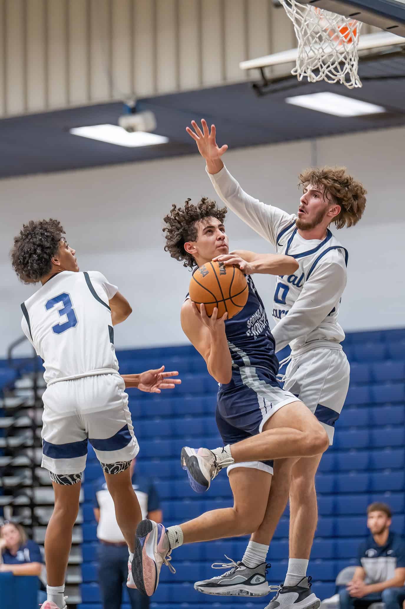 Spring Hill Christian Academy, 25, Matthew Hyde eyes the basket defended by Central High, 3, Marcelo Fonseca and 00, Brayden Prospero. [Photo by Joe DiCristofalo]