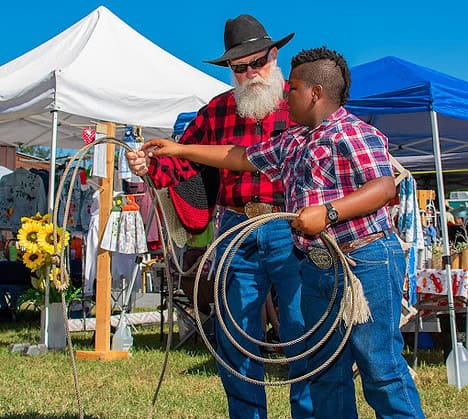 Steve Thistle teaches Jeremiah Prury how to rope a hay bale sheep at the Cowboy Festival November 16, 2024.