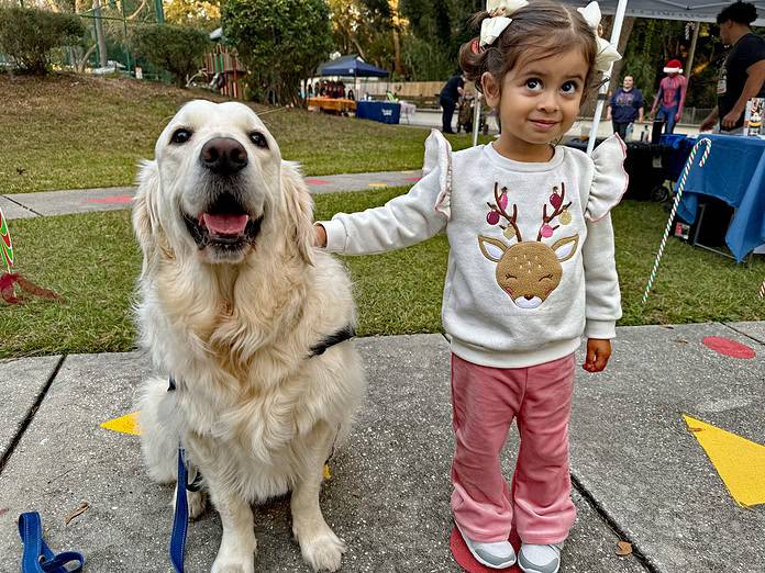 Halo, the caring canine companion shares meet-and-greet with a young event-goer on Thursday. [Photo by John Athanason]