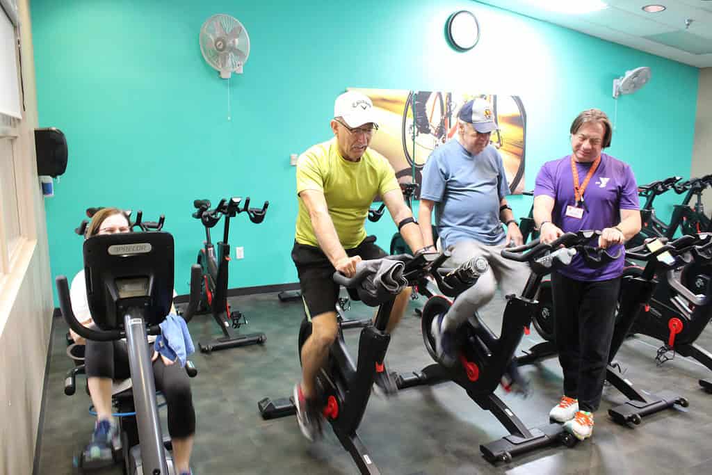 Personal trainer Nelson instructs YMCA members Rafael (left) and Jack on cycling. [Photo credit: Austyn Szempruch]