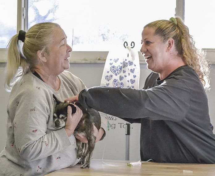 Diane Poulin of Pawsome Pet Care administers fluids to Chuy, who is being held by owner Kimberly Simon. [Credit: Chris Bernhardt Jr.]