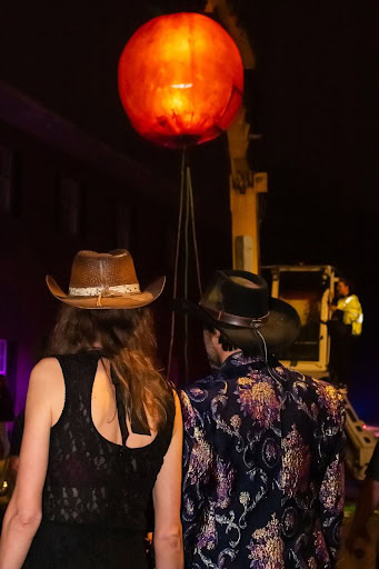 On-lookers watch as the Menzi operators get the tangerine in position for its midnight drop December 31, 2024. [Photo credit Jenifer Truitt]