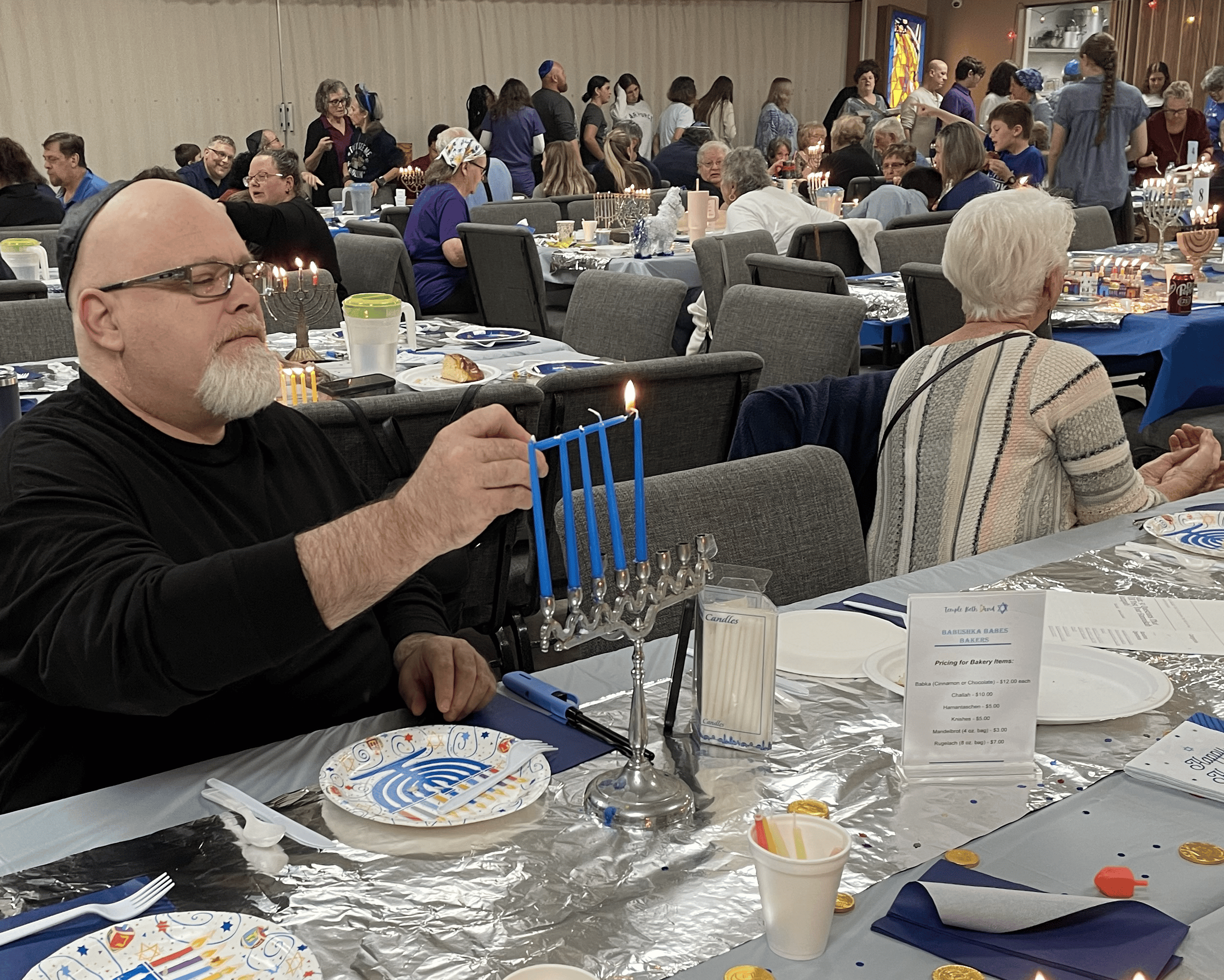 A member of the congregation lighting his personal menorah. [Photo by Sarah Nachin]