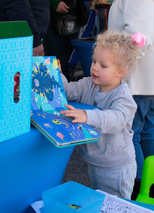 A little girl enjoys browsing books at a vendor tent during Booksville on January 25, 2025. [Photo by Jenifer Truitt]