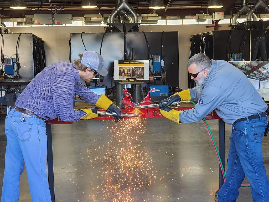 PHSC Welding Program Director Scott Flannery (right) and Welding Program Instructor Jordan Davis (left) cut the "ribbon" with welding torches on Friday. [Photo by Austyn Szempruch]